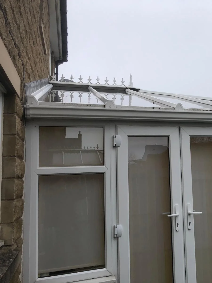 A conservatory built against the house wall, the kind that sits under the main gutter and has to be worked around.