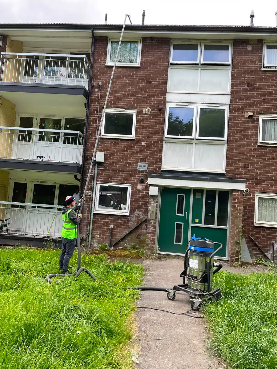 A high reach vacuum pole extended up the side of a three storey building.
